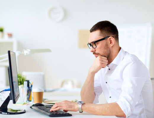 Mitarbeiter IT, seitliches Profil, Blick auf Bildschirm, nachdenkliche Pose, tippt auf Keyboard