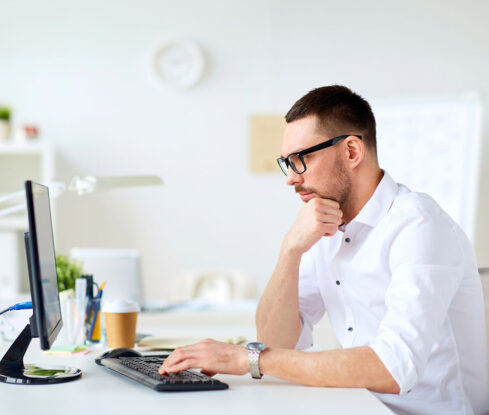 Mitarbeiter IT, seitliches Profil, Blick auf Bildschirm, nachdenkliche Pose, tippt auf Keyboard